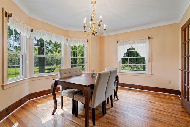 dining area with light wood-type flooring and a notable chandelier