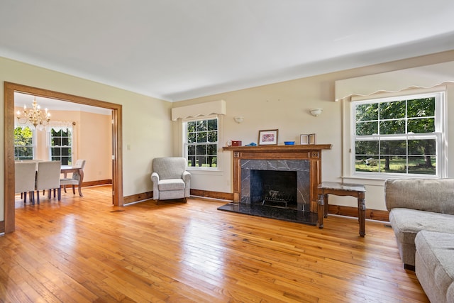 living room with a fireplace, a notable chandelier, and light wood-type flooring