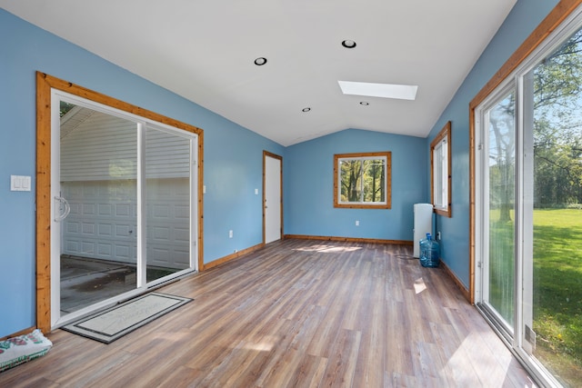 unfurnished room with vaulted ceiling with skylight and light hardwood / wood-style flooring