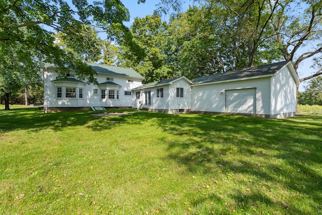 back of house featuring an outbuilding, a garage, and a lawn