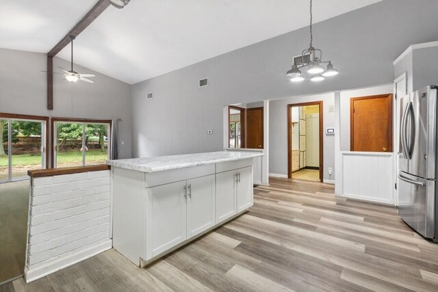 kitchen with white cabinets, ceiling fan with notable chandelier, hanging light fixtures, light hardwood / wood-style floors, and stainless steel refrigerator