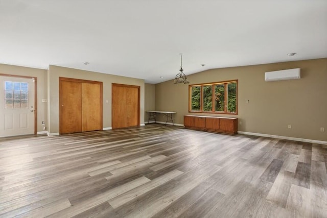 5544 Wendzel Dr, Coloma, MI 49038 - unfurnished living room with wood finished floors, a wall unit AC, baseboards, lofted ceiling, and a chandelier