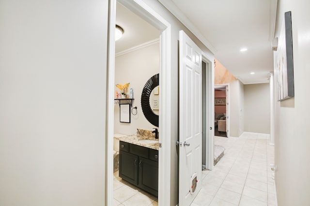 corridor with sink, light tile patterned floors, and crown molding