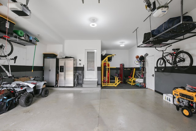 garage featuring a garage door opener and stainless steel refrigerator with ice dispenser