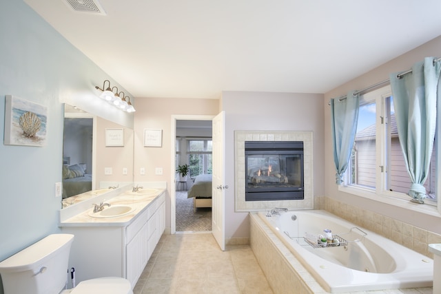 bathroom with tiled tub, a wealth of natural light, tile patterned flooring, and vanity