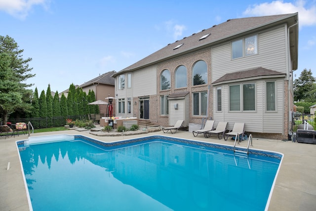 rear view of property with a fenced in pool and a patio area