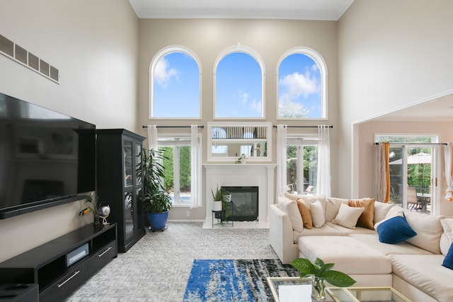 carpeted living room featuring ornamental molding and a high ceiling