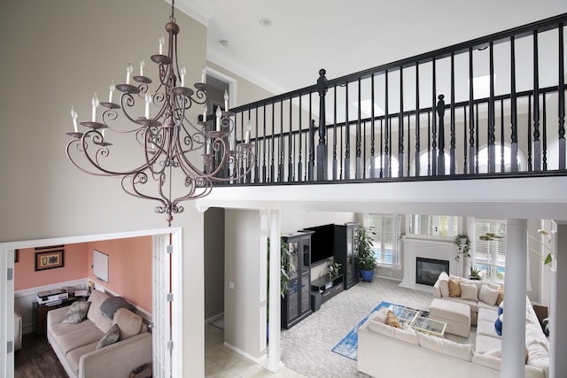 living room featuring a towering ceiling, a chandelier, and ornamental molding