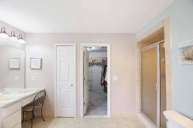 bathroom featuring tile patterned flooring, vanity, toilet, and walk in shower