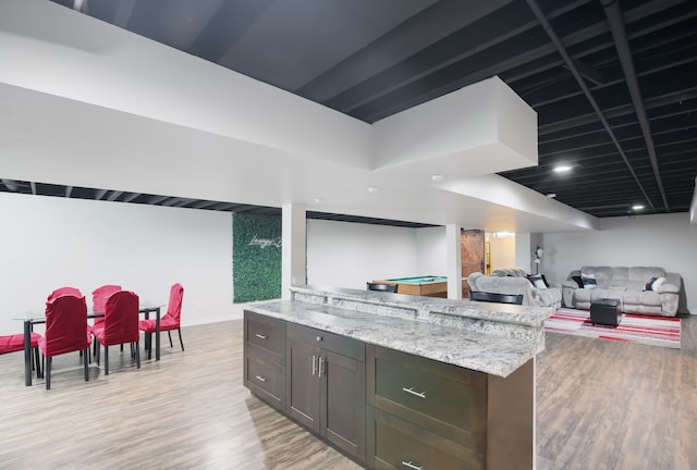 kitchen featuring dark brown cabinets, light hardwood / wood-style floors, and light stone counters