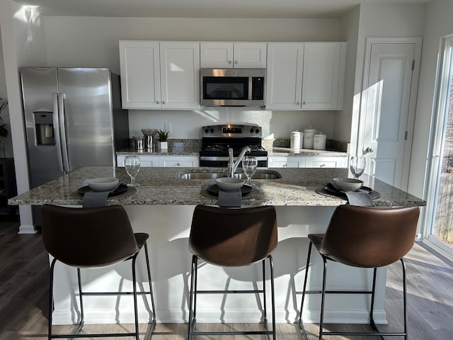 kitchen with stainless steel appliances, white cabinets, and light stone counters