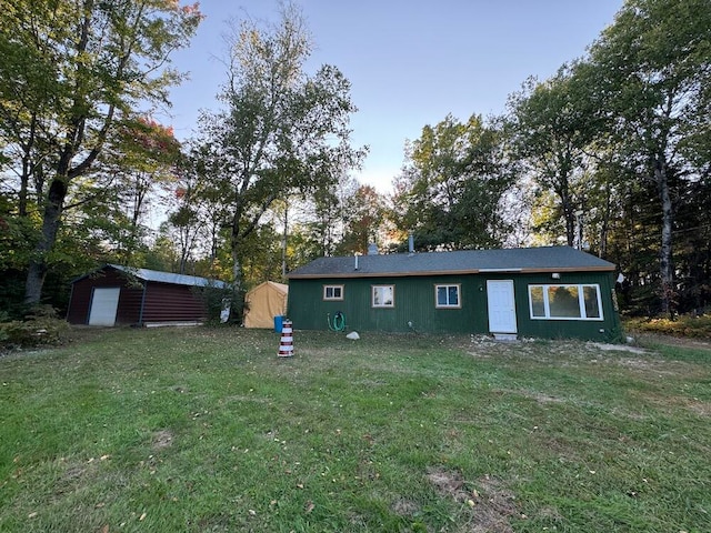 back of house featuring a lawn and a storage unit