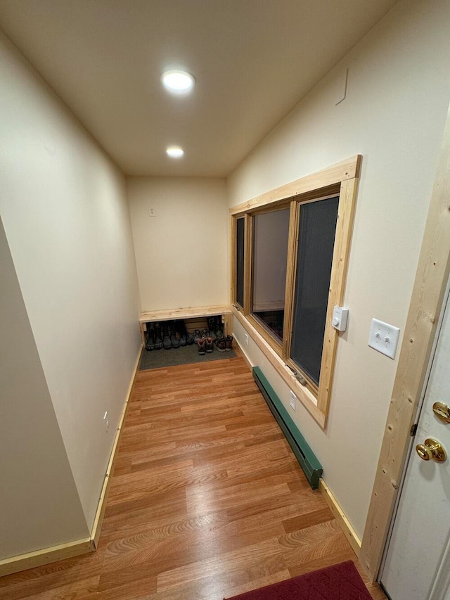 hall with light wood-type flooring and a baseboard heating unit