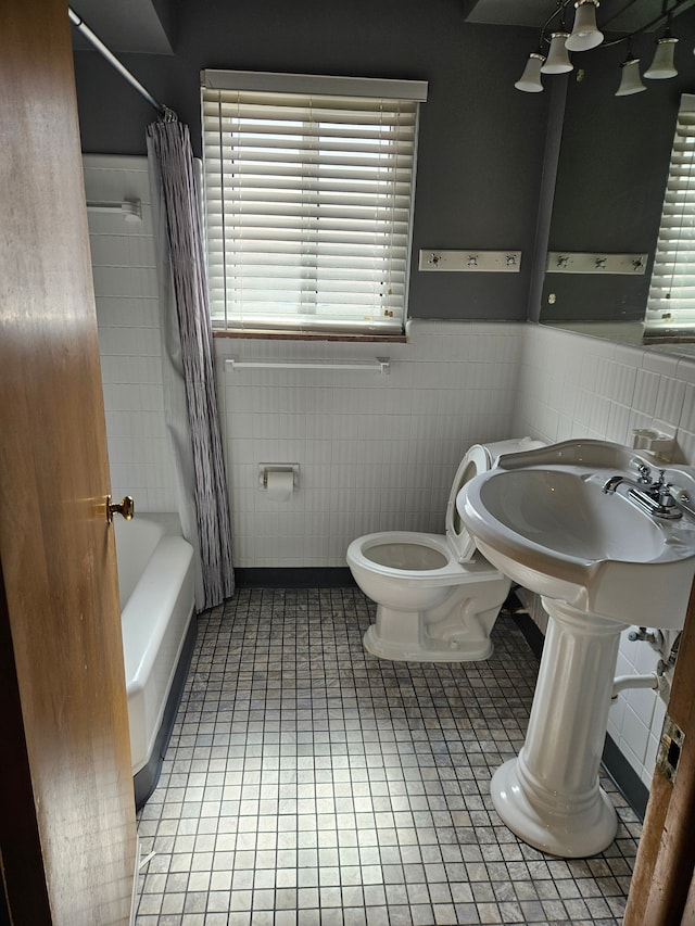 bathroom with tile patterned flooring, toilet, tile walls, and shower / tub combo