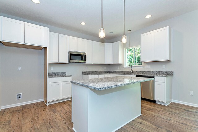 kitchen featuring light wood-type flooring, stainless steel appliances, a center island, and white cabinetry