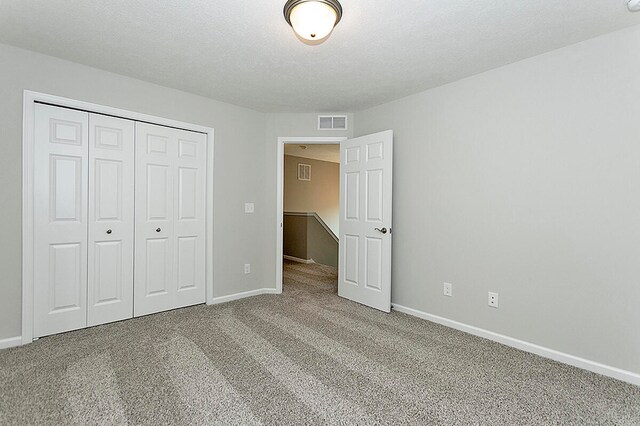 unfurnished bedroom featuring visible vents, baseboards, carpet, and a closet