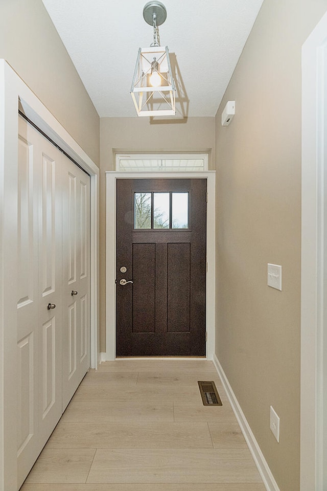 doorway featuring light wood-style floors, visible vents, and baseboards