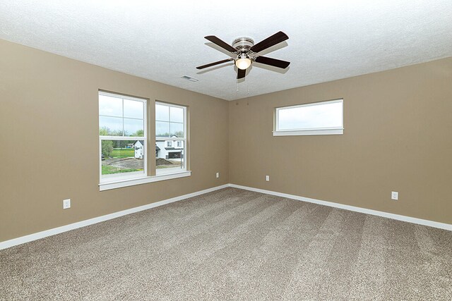 empty room with a ceiling fan, visible vents, baseboards, carpet floors, and a textured ceiling