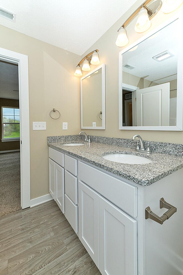 full bathroom with visible vents, wood finished floors, baseboards, and a sink