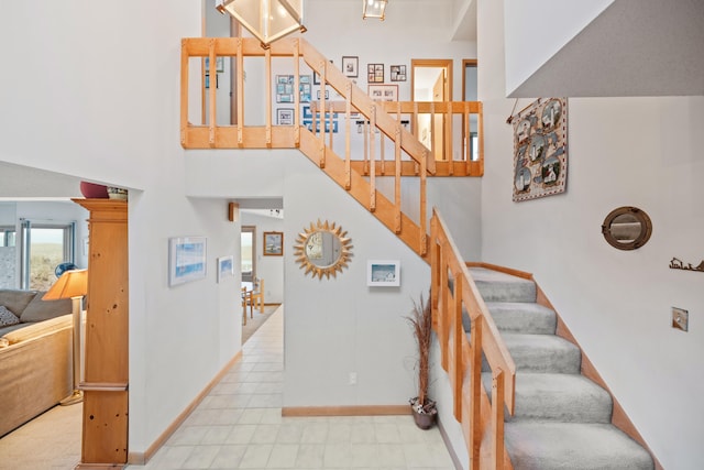 staircase with baseboards and a towering ceiling