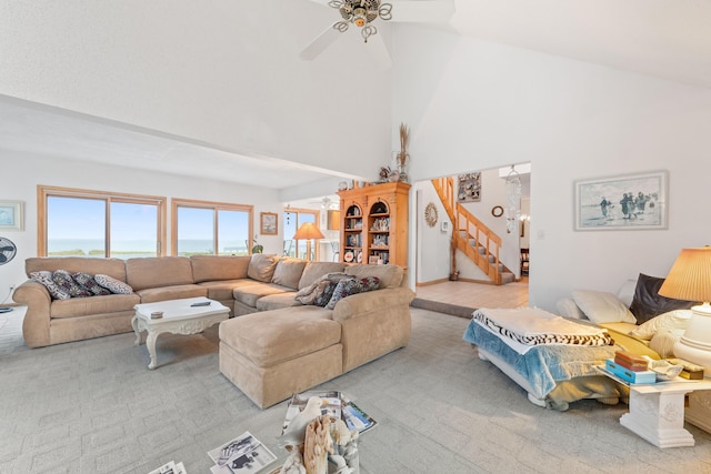 carpeted living room featuring a ceiling fan, stairs, and a towering ceiling