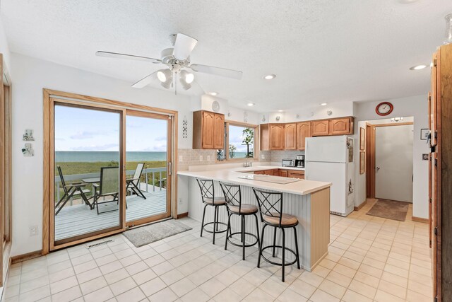 300 Marquette Dr, New Buffalo, MI 49117 - kitchen featuring freestanding refrigerator, a peninsula, a breakfast bar, light countertops, and tasteful backsplash