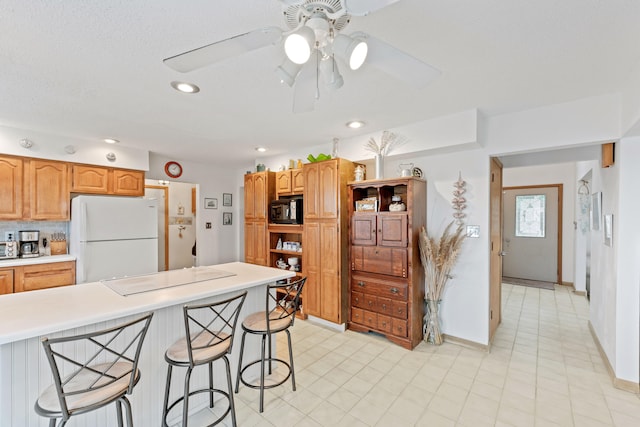 kitchen with a breakfast bar, freestanding refrigerator, open shelves, black microwave, and light countertops