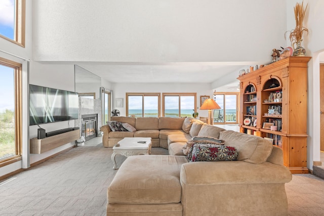 living room with light carpet, a high ceiling, and a glass covered fireplace