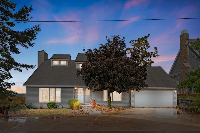 view of front of property featuring roof with shingles, an attached garage, a chimney, and driveway