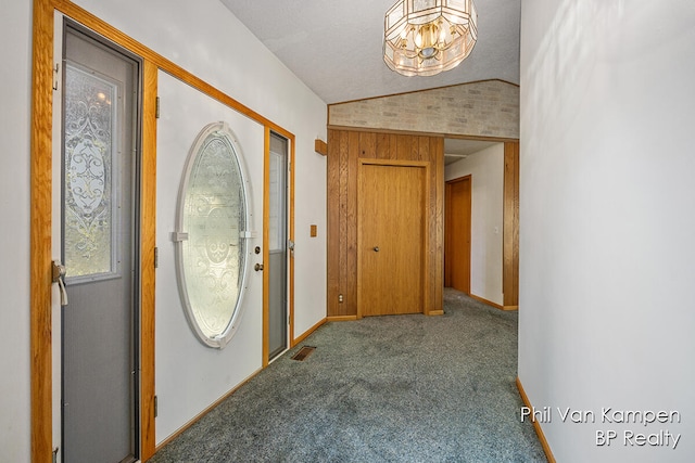 foyer featuring carpet flooring, a chandelier, and vaulted ceiling