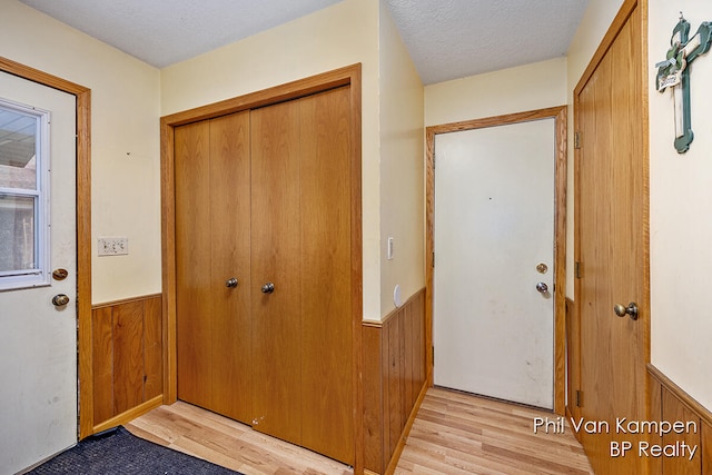 foyer entrance featuring wooden walls, light hardwood / wood-style floors, and a textured ceiling