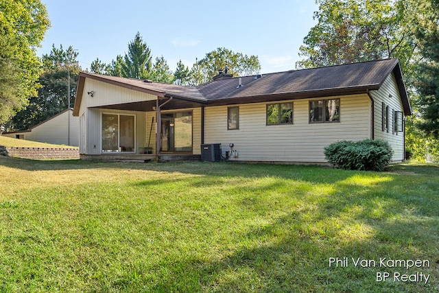 back of house featuring a lawn and central air condition unit