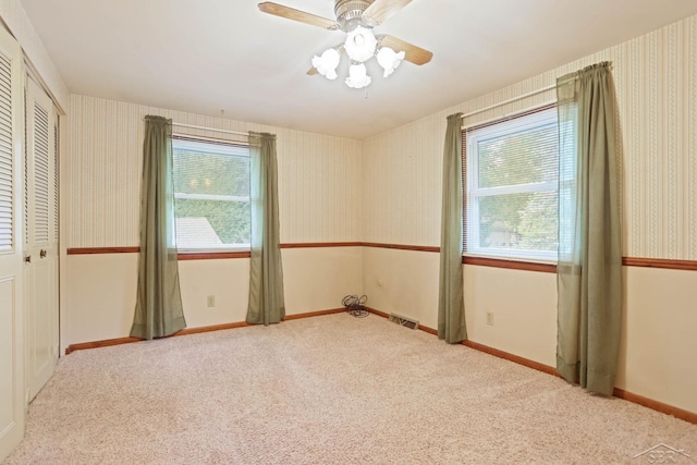 spare room with ceiling fan and light colored carpet