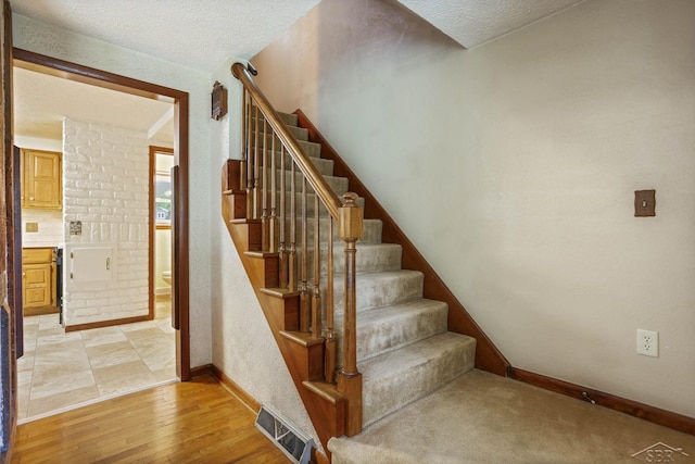 staircase with wood-type flooring and a textured ceiling