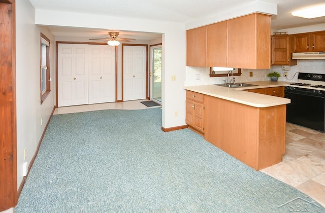 kitchen with sink, ceiling fan, decorative backsplash, white gas stove, and kitchen peninsula