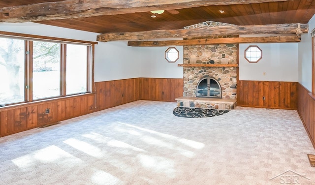 unfurnished living room with a fireplace, light colored carpet, wood walls, and wood ceiling