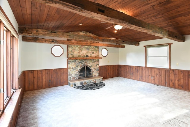 unfurnished living room with carpet, a stone fireplace, and a wealth of natural light