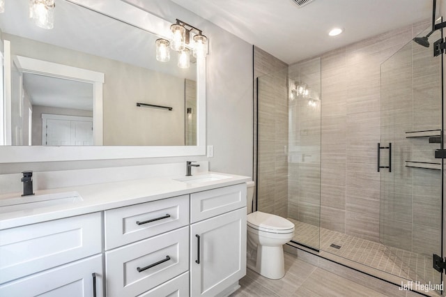 bathroom featuring vanity, toilet, and a shower with shower door