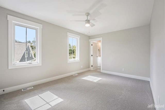 carpeted spare room featuring ceiling fan and a healthy amount of sunlight