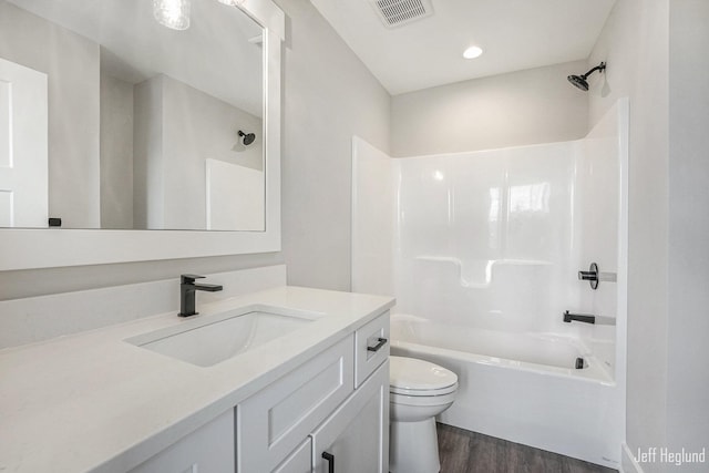 full bathroom featuring washtub / shower combination, wood-type flooring, vanity, and toilet