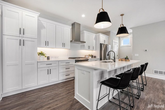 kitchen featuring white cabinets, hanging light fixtures, and wall chimney range hood