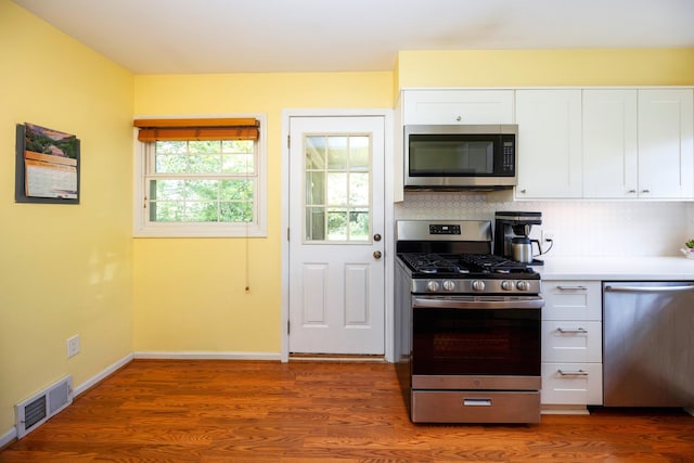 kitchen featuring white cabinets, wood-type flooring, stainless steel appliances, and tasteful backsplash