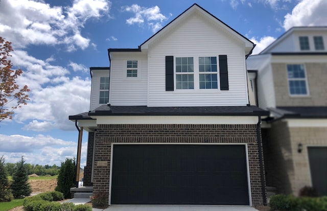 traditional-style home featuring a garage, concrete driveway, and brick siding