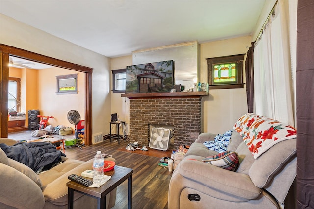 living room with dark hardwood / wood-style flooring and a brick fireplace