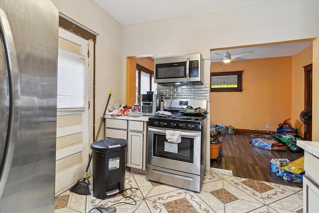 kitchen with backsplash, ceiling fan, light wood-type flooring, and appliances with stainless steel finishes