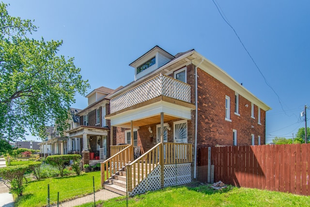 view of front of house featuring a balcony and a front yard