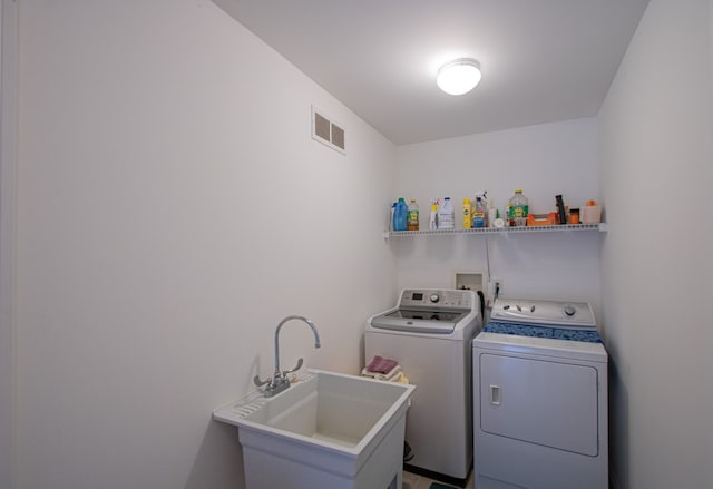 clothes washing area with separate washer and dryer and sink