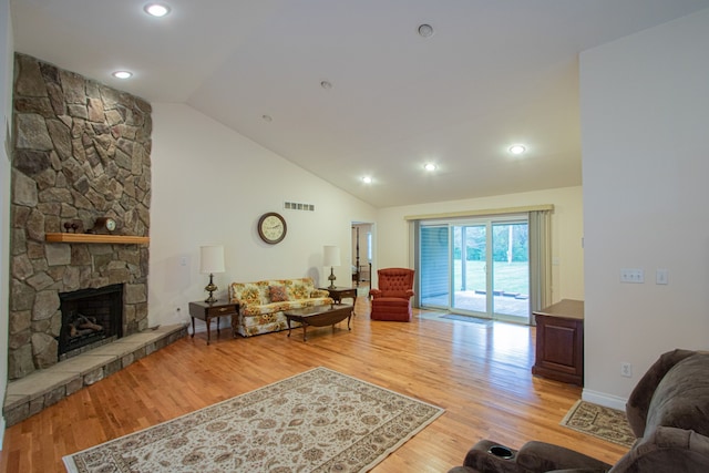 living room featuring a stone fireplace, light hardwood / wood-style flooring, and high vaulted ceiling