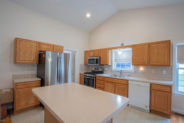 kitchen featuring sink, a center island, stainless steel appliances, tasteful backsplash, and high vaulted ceiling