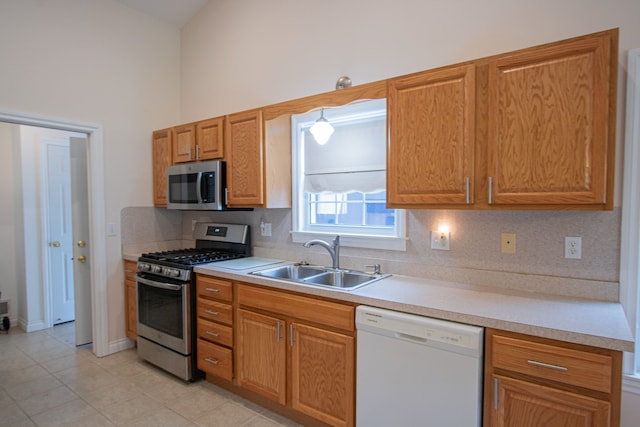 kitchen with backsplash, sink, light tile patterned floors, appliances with stainless steel finishes, and decorative light fixtures